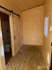 Barn door to bath with room for a bed.