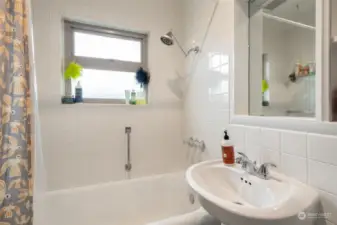 White tiled bathroom with a pedestal sink, good storage, and vintage tile floors.