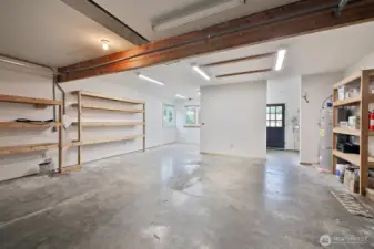 Spacious 2 Car Garage with plenty of built-in storage and an EV Charger. The hot water heater is located here and there is additional space beyond the partial wall straight ahead. The door to the house is along the right edge of photo.