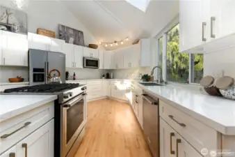 This gourmet kitchen features all-new cabinetry, sleek quartz countertops, appliances, and a custom island that offers a generous space for food prep, casual dining, and effortless entertaining.