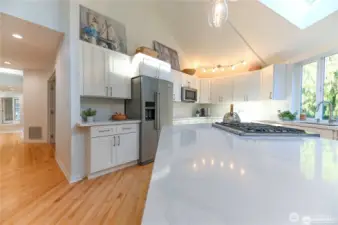This view highlights the new sleek quartz countertops, cabinetry, kitchen appliances and the beautifully refinished floors and brand-new carpeting throughout.
