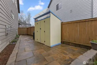 Low maintenance and laid patio stones with storage shed