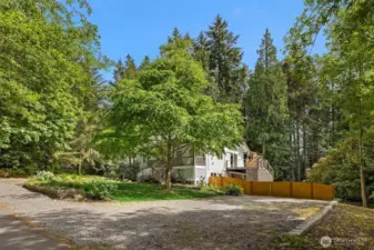 The property is nearly an acre of all organic landscaping, with half the backyard fully-fenced for kids or pets, and the other half native woodland with invasive species lovingly removed by the current owners. Out front, you’ll find sweet English-style cottage gardens, a wide driveway leading to the garage, and on the opposite side this huge parking pad with ample room for an RV or boats.