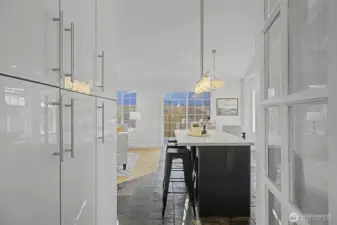 From the dining room or home office, enjoy clean sightlines into the open kitchen and adjoining great room, highlighting the home’s cohesive layout and easy flow. Glossy hard-surface cabinetry, quartz counters and modern pendant lighting create a polished, contemporary look, while warm wood floors soften the space and add warmth. This thoughtful connection keeps living, dining and entertaining spaces seamlessly integrated.