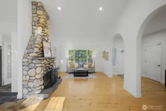 A striking floor-to-ceiling river rock, wood-burning fireplace anchors the great room and creates a warm, lodge-inspired focal point. Wide-plank wood floors, recessed lighting and soft natural light enhance the inviting atmosphere, while elegant arched openings add architectural character and define the flow between living spaces. This stunning feature brings both visual impact and everyday comfort to the heart of the home.