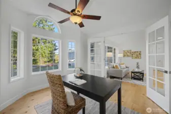 This light-filled room offers exceptional flexibility as a formal dining space or a private home office. Tall windows, an arched transom window and warm wood floors create an inviting atmosphere, while French doors open to the formal living area for an easy, connected flow. A ceiling fan and soft natural light enhance comfort, making this an ideal space for remote work, quiet reading or elegant gatherings.