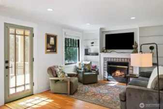 A gas fireplace is the centerpiece of the living room, where built-in glass shelving allows for fun decorating in all seasons. (The television will convey with the home.)