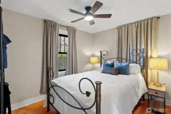 A main-level bedroom enjoys original refurbished Douglas fir flooring, a new ceiling fan, and new windows.