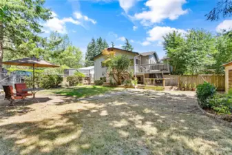 A view of the backyard facing the house & back deck. There is a fenced, raised garden area near the house and easily accessed from the kitchen area.