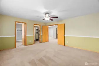 Primary bedroom with the 5 piece bath showing through the left door, a big walk-in closet and double doors to the large loft area.