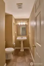 Main Floor Half Bathroom with Tile Floors and Newer Light Fixture.