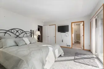 Main level primary bedroom showing doorway to full bath w/jetted tub. Walk-in closet behind door.
