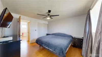 Comfortable primary bedroom with warm wood-style flooring and abundant natural light.