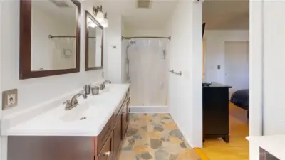 Primary bath features a dual-sink vanity, updated cabinetry, and a spacious layout with direct access from the bedroom.