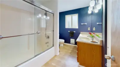 Hall bath with a spacious vanity, updated lighting, and a tub/shower combo with sleek glass doors.
