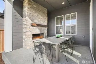 Covered patio with exterior fireplace.  Photo taken from similar model