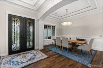 A stunning grand entry showcases coffered ceilings, elegant French doors, and exquisite millwork, all beautifully accented by recessed lighting.