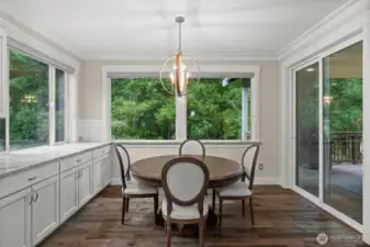 The informal dining area off the kitchen overlooks a lush, green backyard. Whether you choose to dine indoors or on the adjoining covered deck, both spaces offer year-round comfort and enjoyment.