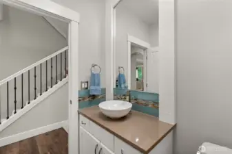 A powder room just off the kitchen showcases a raised vessel sink paired with a counter-to-ceiling framed mirror, offering a refined yet understated presentation.