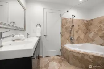 Hallway bathroom featuring a double sink and an extra-large bathtub.