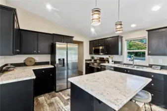 Slab quartz and added backsplash stainless appliances including fridge, microwave, dishwasher, and oven cooktop
