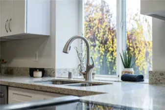 A generous window over the kitchen sink invites light and spaciousness into the kitchen.