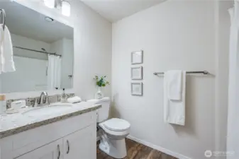 Features of the primary suite bathroom include an updated vanity with quartz countertop, new toilet, new mirror, new light fixture, and new flooring.