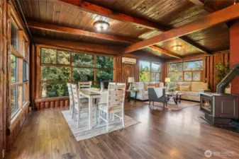 Open concept kitchen, dining and living room with floor to ceiling windows and vaulted ceilings