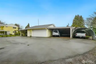 Rear of home with 2 car carports on both right and left of oversized 2 car garage, plus another covered parking area and covered porch area on far left of photo.