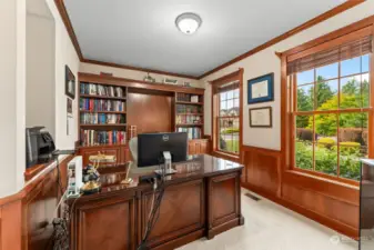 Stately home office with French doors and rich woodwork including generous built-in cabinetry.