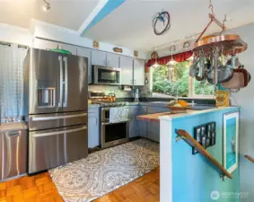Open kitchen with stainless steel appliances and bay window.
