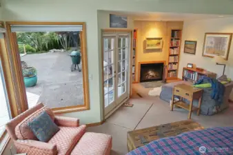 Another view of the primary suite, with french doors opening to the spacious back deck, and another fireplace and cozy reading area.