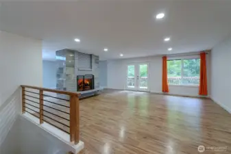 The grand living room on the main level is bright with the natural light. French doors open to a large deck that extends along much of the house and overlooks the nature preserve to the west. The beautiful marble surround of the fireplaces is central in the kitchen, dining and living rooms, helping to define each room. Recessed lighting above, LVP flooring and soundproofing below, this house provides options for separate residences on two levels.