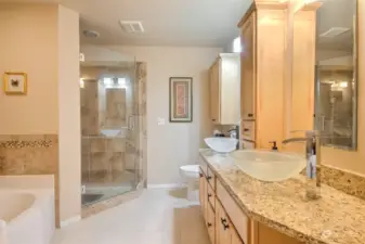 Stunning primary bathroom with new tile floors, tile shower w/ 3/4 glass door, above counter sinks so you don't have to bend so far, new fixtures & lights, granite counters & tile surround on the tub