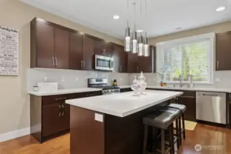 Chef's kitchen with oversized island, quartz countertops, with hardwood floors throughout.
