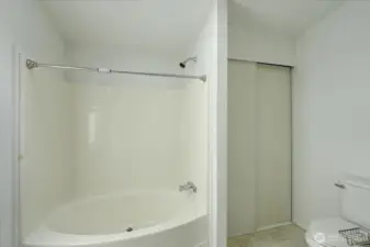 Primary bath with large soaking tub and linen closet.