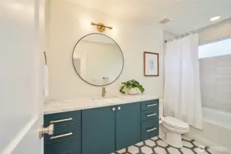 The luxurious hall bath on the top level offers plenty of storage and boasts quartz countertops, undermount sink, tile flooring West Elm lighting and a beautiful tiled tub surround with a transom window for light yet privacy.