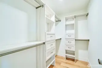 The primary suite's walk in closet is complete with a storage system with soft close drawers.