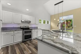 Kitchen w/ timeless white cabinets, slab stone countertops, glass backsplash & double oven.