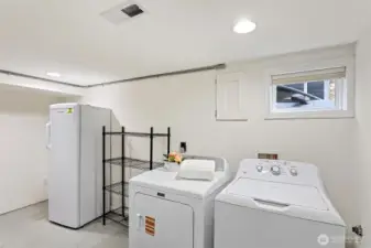 Lower level utility room with W/D, freezer and shelving and access to the furnace and water heater.