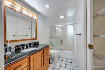 Upper level full bathroom with tile flooring, one piece shower surround, slab granite counter and linen closet.