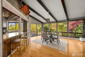 Large windows showcase the view and bathe the room in natural light. Breakfast nook and kitchen eating area. A second oversized glass sliding door on the main leads to the expansive deck.