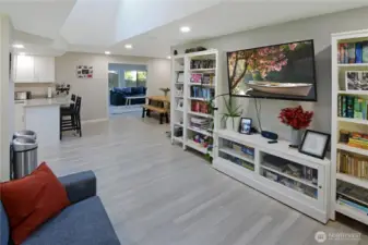 Bright main living room with LVP flooring, skylight for abundant natural light, and open flow to the kitchen, dining area, and spacious new family room.