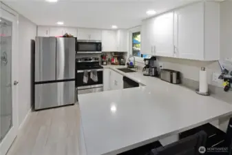Kitchen view with quartz countertops, breakfast nook seating, and walk-in pantry with glass door—stylish and functional Bonney Lake rambler kitchen.