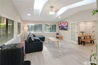 Spacious family room with four skylights, abundant natural light, and new pellet stove for efficient heating—bright and inviting space overlooking the dining area.