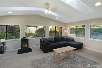 Family room with vaulted ceiling, multiple skylights, LVP flooring, and surrounding windows—light-filled Bonney Lake rambler living space.