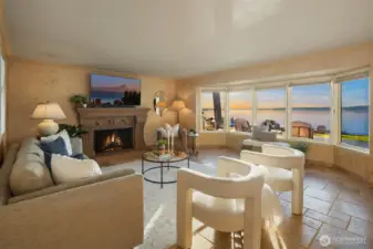 Cozy up by the fireplace in this light-filled family room, offering peaceful water views that create a serene atmosphere.