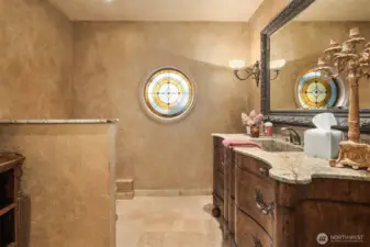 Showcasing artisan-level details, the powder room boasts a rare stained glass piece that acts as a stunning focal point.