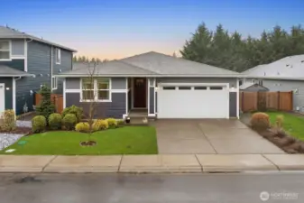 Front exterior view of a single-story home in Bonney Lake’s Falling Water community featuring a covered entry, attached two-car garage, landscaped front yard, and concrete driveway along a quiet residential street.