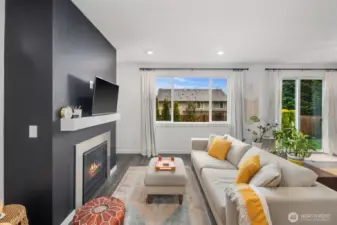 Living room with modern fireplace feature wall, floating mantel, large picture window, and seating area positioned to capture natural light and backyard views.